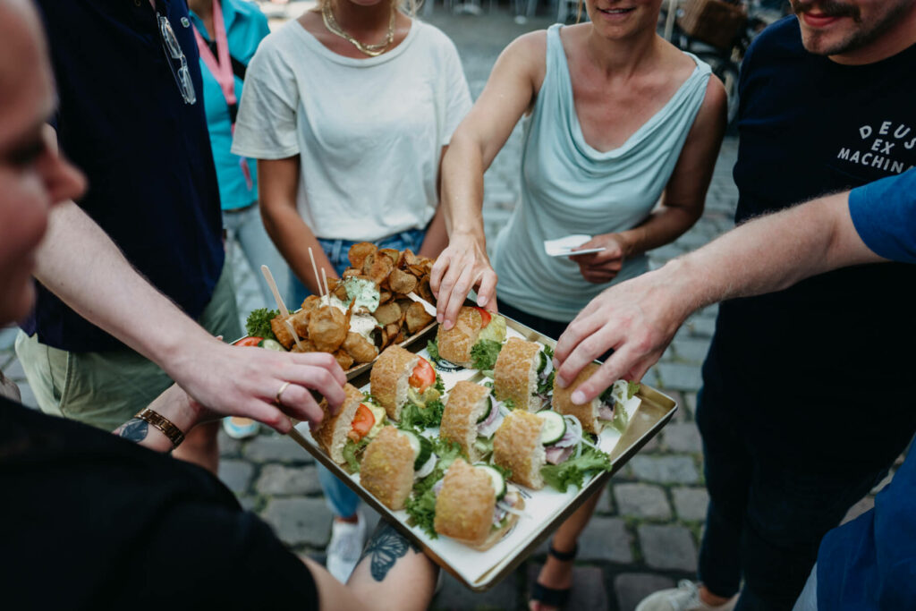 Eine Gruppe von Menschen nimmt sich jeweils ein Fischbrötchen.