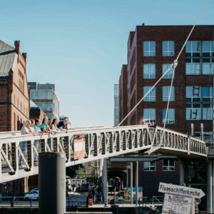 Eine Gruppe von Menschen steht auf einer Brücke, die sich über einen Fluss erstreckt.