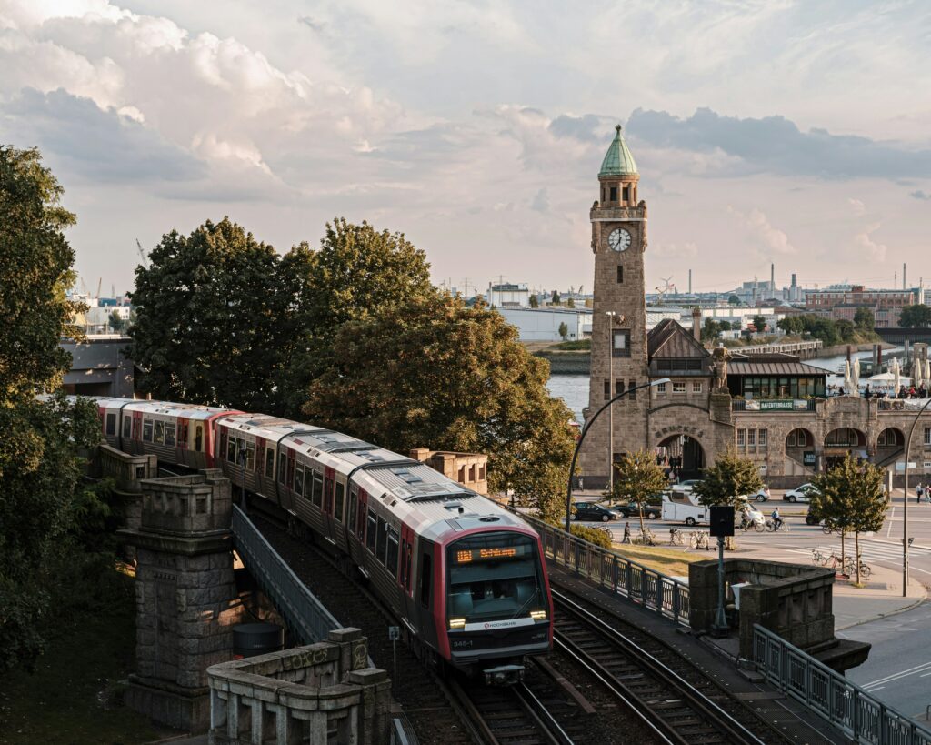 Im Vordergrund zieht eine U-Bahn vorbei, während im Hintergrund die Landungsbrücken zu sehen sind.